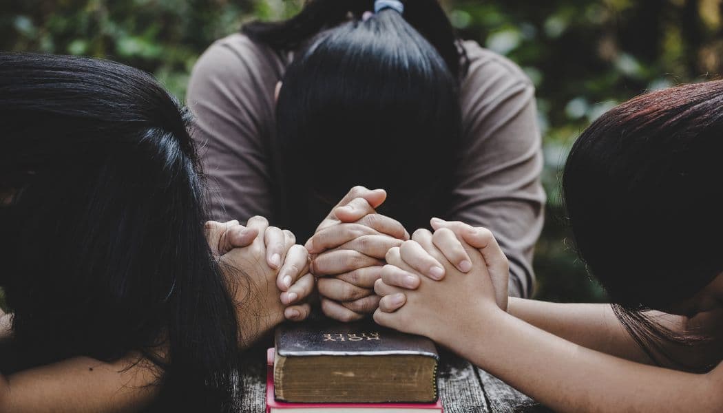 mulheres orando na mesma com a Bíblia
