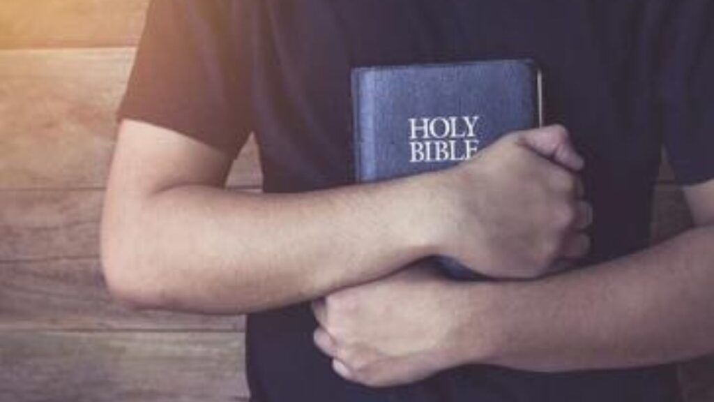 homem enlutado abraçando a Bíblia