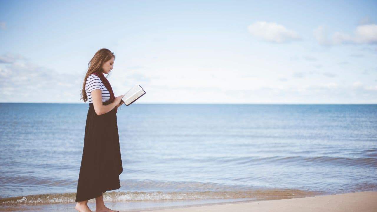 mulher sábia lendo a bíblia na praia